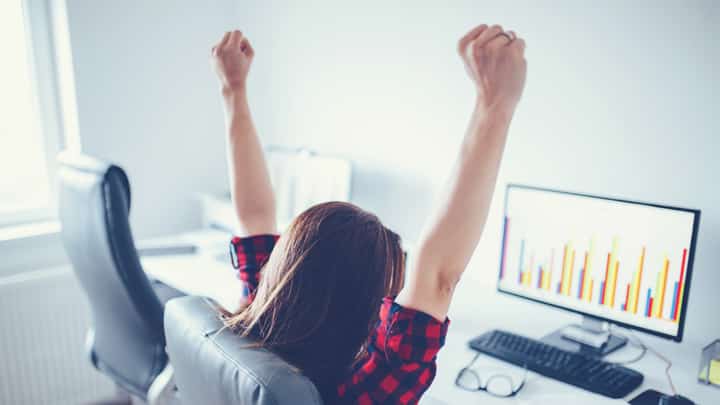 Lady looking at a computer screen with her arms in the air