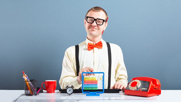 Man in glasses and red bow tie at desk with toy abacus