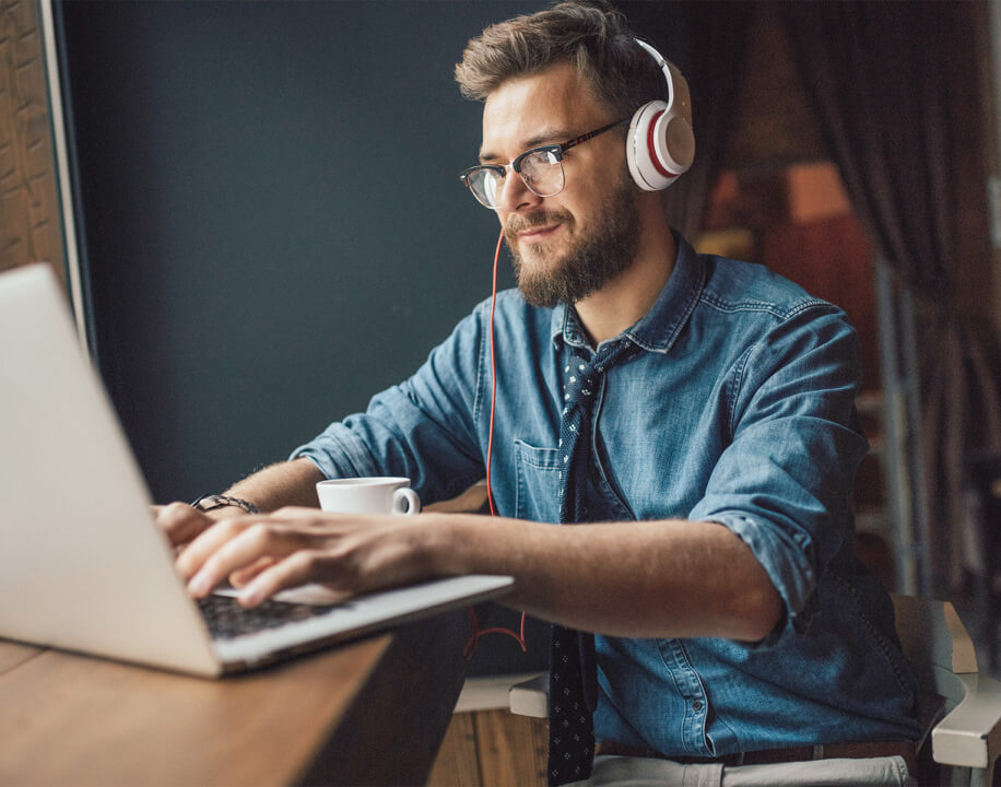 man working on a laptop with headphones on