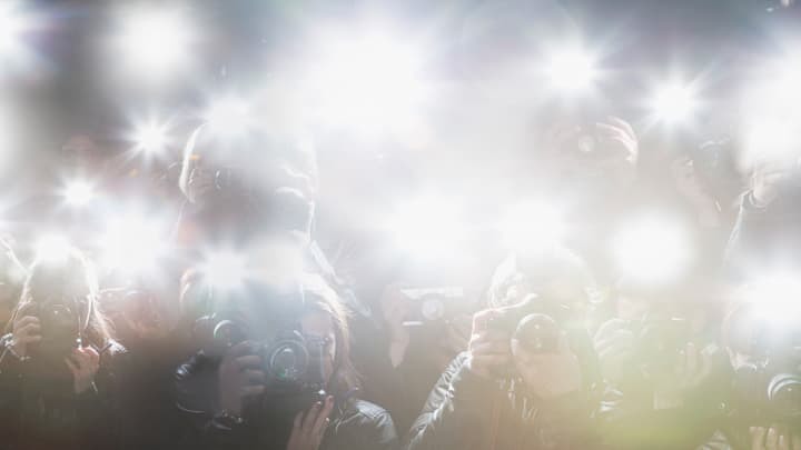 Flashing cameras as a group of people take photographs