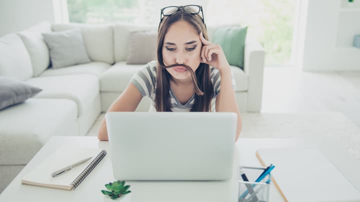 woman at desk looking at laptop with hair across her lip like a moustache