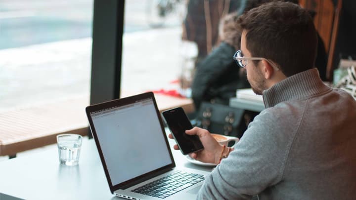 man at laptop with mobile phone