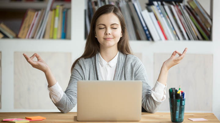 Woman meditating in front of laptop