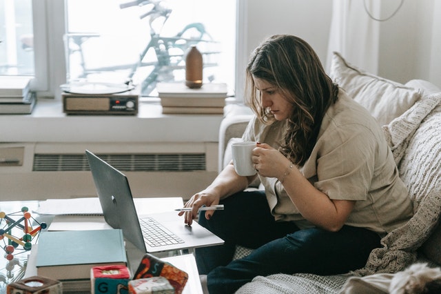 A lady working on a laptop holding a cup