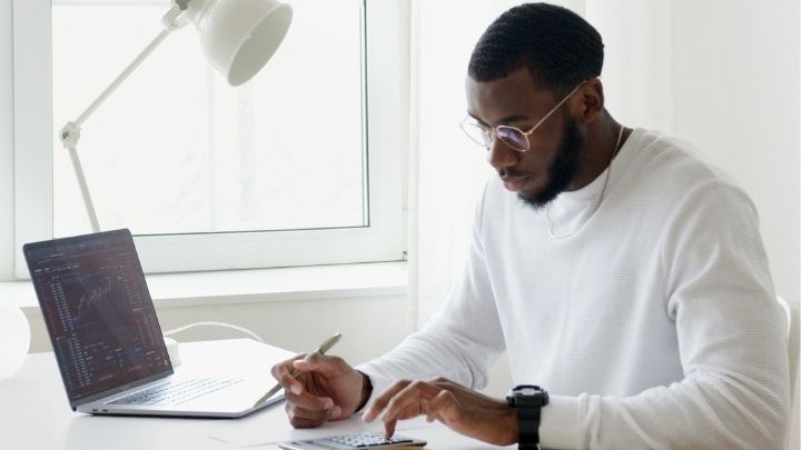 A man working at a desk with a laptop and a calculator