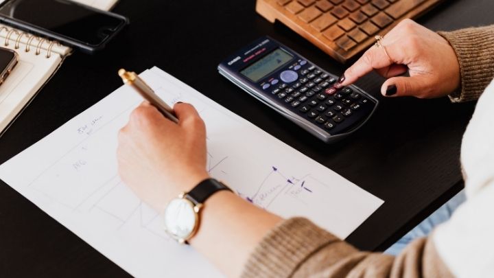 A lady writing and using a calculator