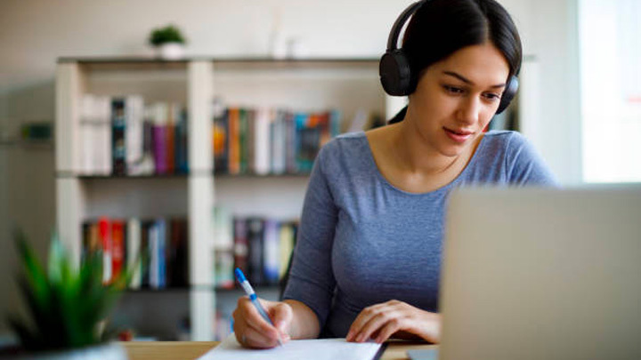 A lady working at a desk wearing headphones