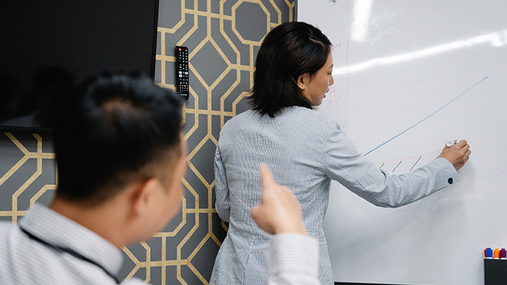 A lady drawing a graph on a white board