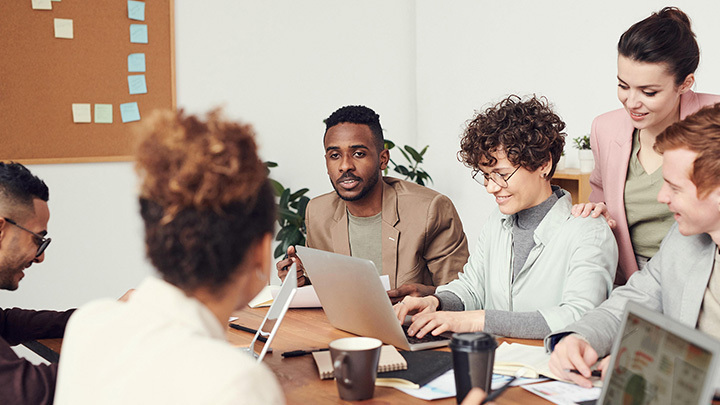 Group of people around a table working on laptops