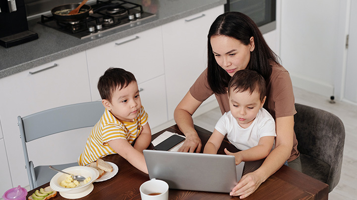 Female parent on laptop with two small children