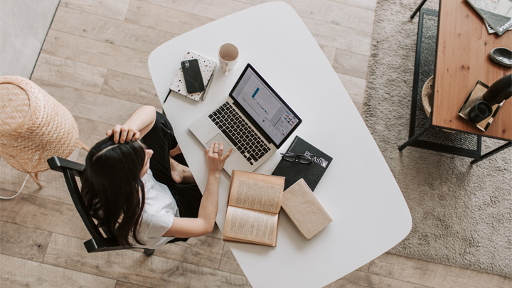 Bird's eye view of a woman sitting at her desk, working on a laptop