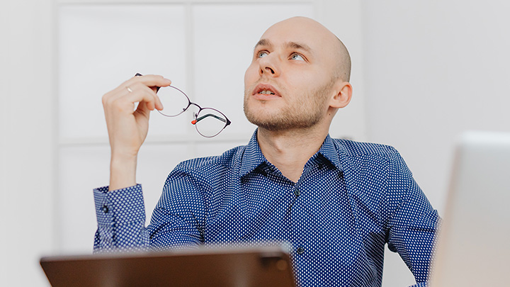 Man looking up to sky, holding glasses