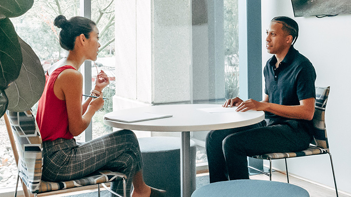 Man and woman sat at table, in discussion