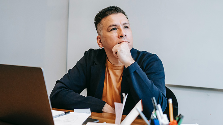 Man at desk, looking off into the distance