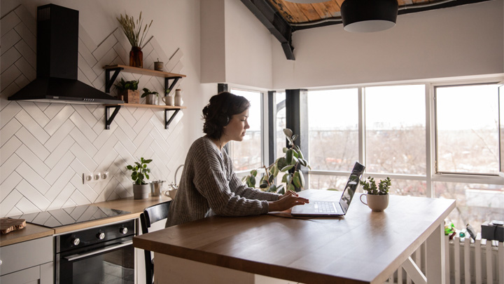 Woman in kitchen working on laptop