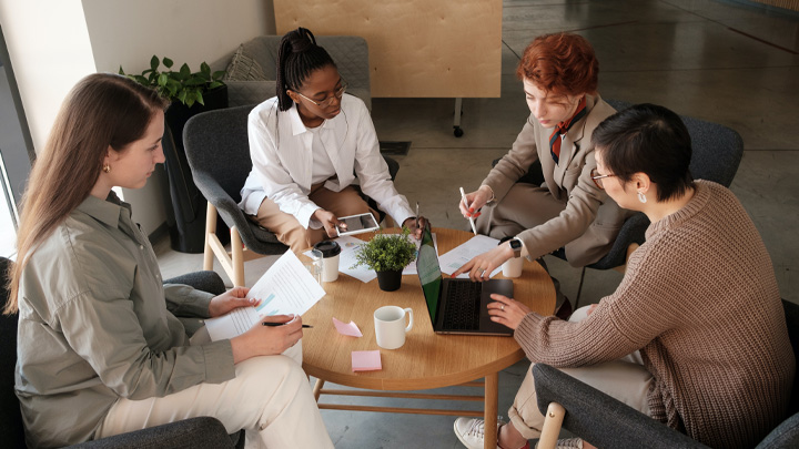 Four people sat around a low table, working on laptops and paperwork