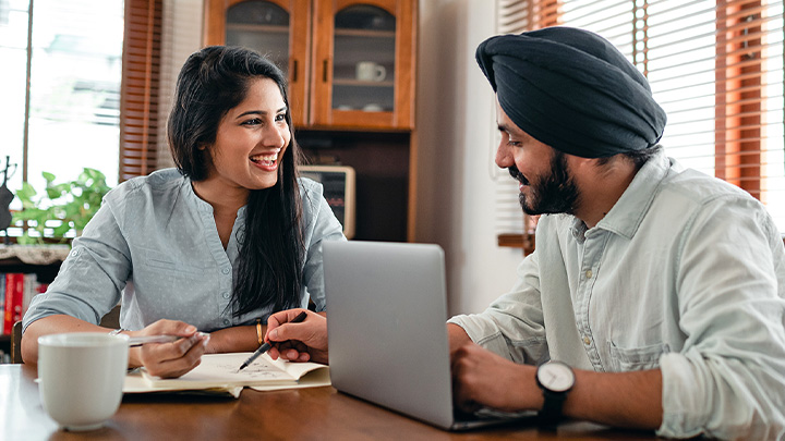 Two people talking at table with laptop