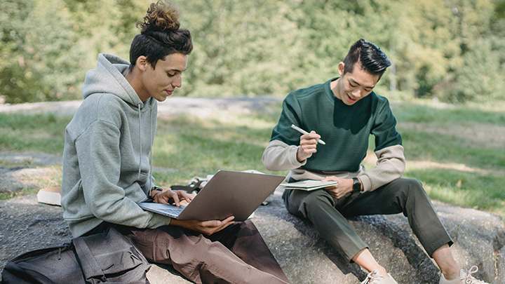 Two people sitting outside working