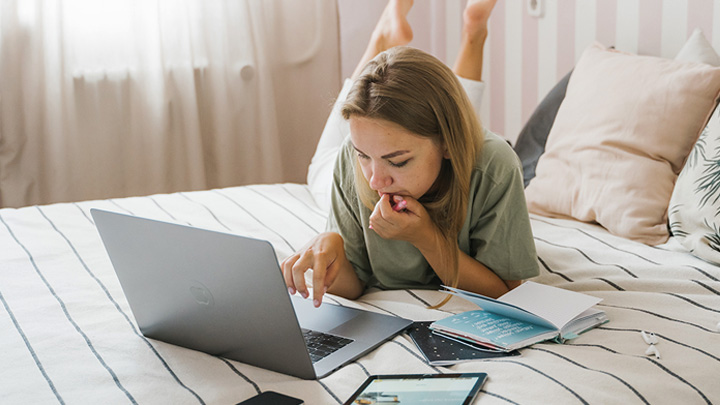 Woman on bed working on laptop