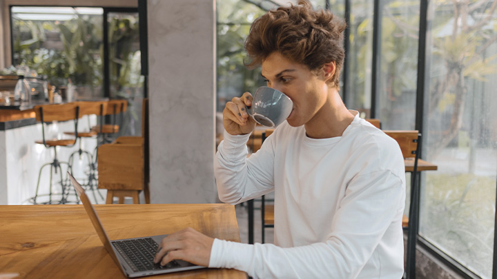 Man working on laptop drinking from cup