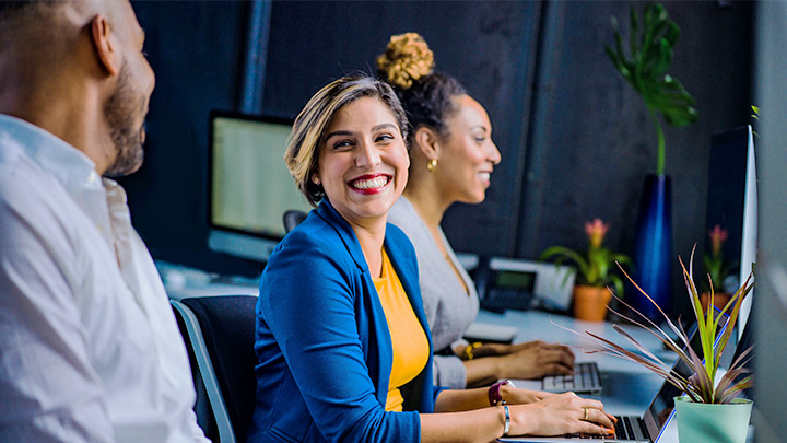 Woman at desk smiling at man next to her