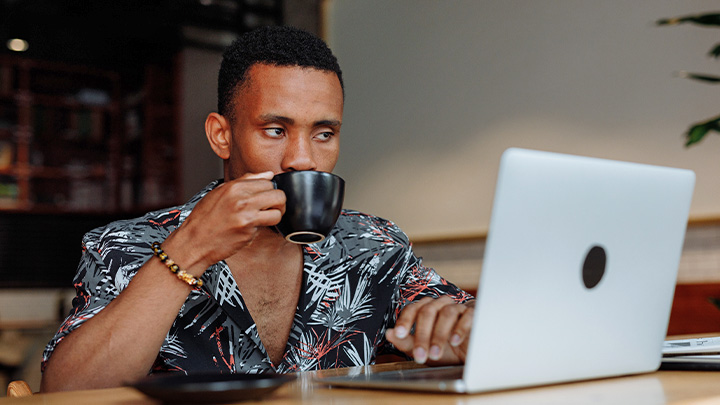 Man at laptop with cup of coffee