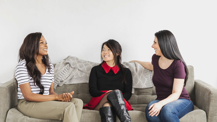 Three women smiling on a sofa