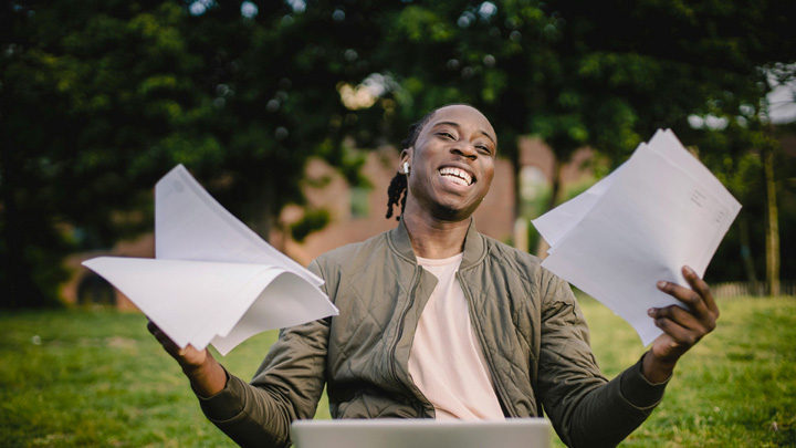 Man smiling holding pieces of paper in each hand