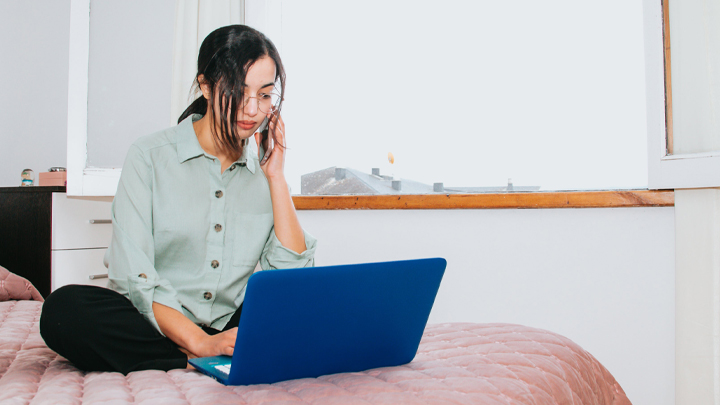 Woman working from home on laptop on bed