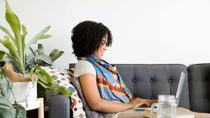 Woman working on laptop, sat on a sofa