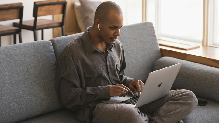 Man sitting on sofa, working on laptop