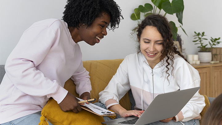 Two women smiling at laptop