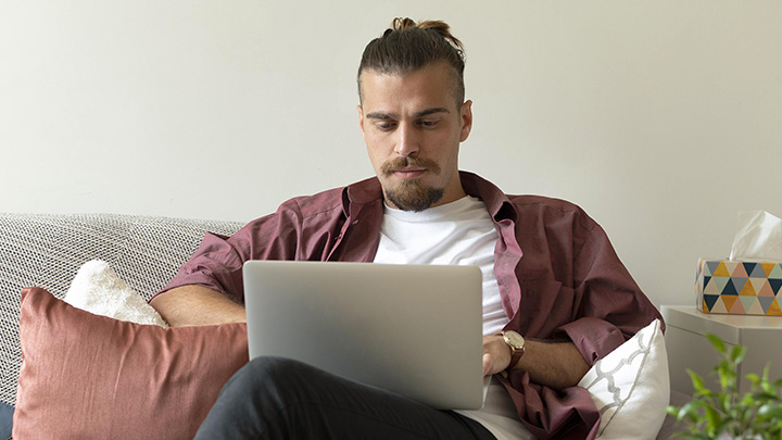 Man sat on sofa with laptop, working from home