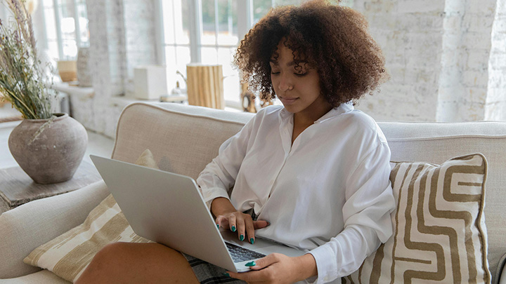woman sat on sofa with laptop