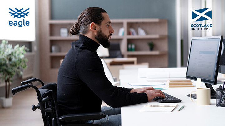 Man sat at desk, in wheelchair, working at a computer