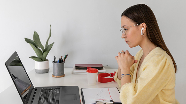 Woman working at desk, looking at laptop