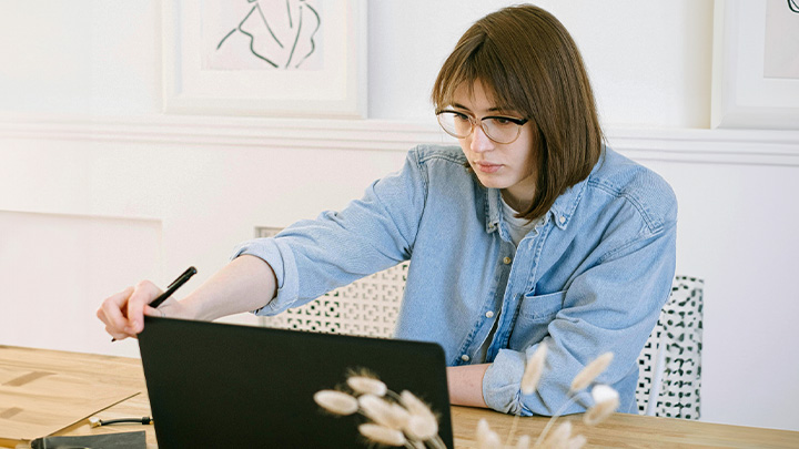 Woman sat at table, looking at laptop