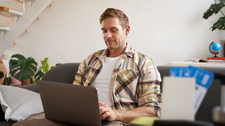 Man sat on sofa, working on laptop