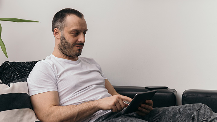 Man sat on the sofa, using a tablet computer